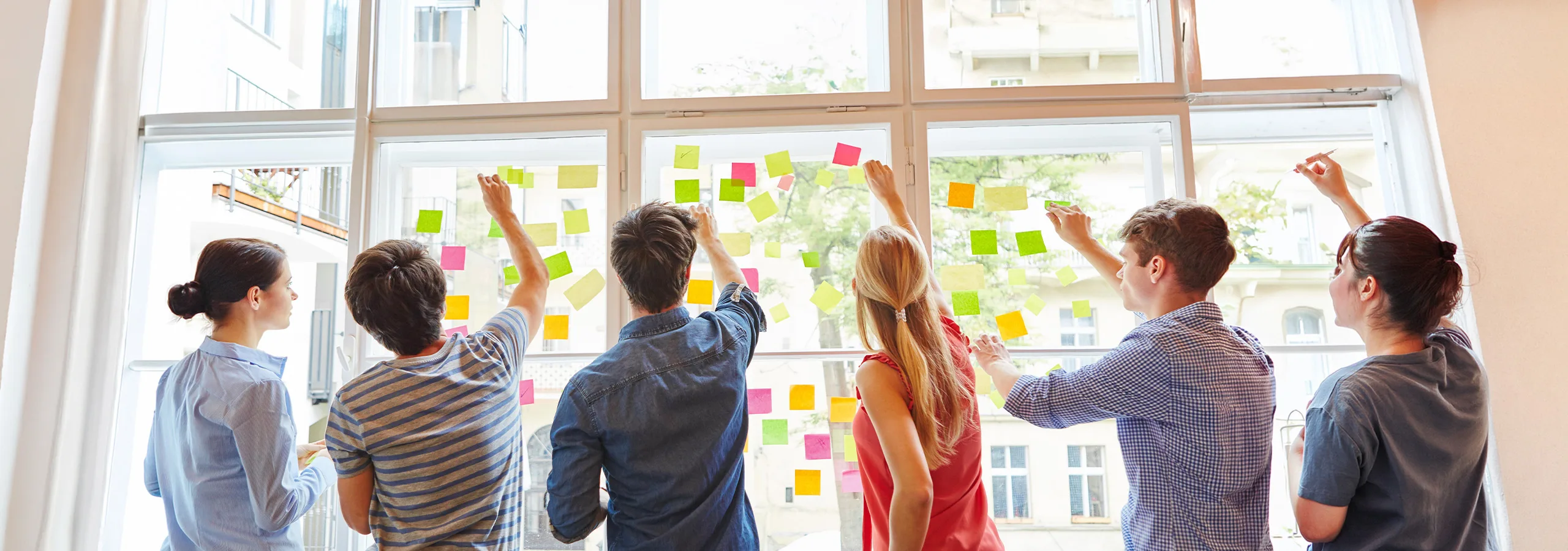 The team mapping ideas on sticky notes across a bright studio window